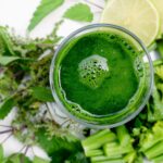 Bevanda verde detox in un bicchiere, circondata da ingredienti freschi per la purificazione del fegato.